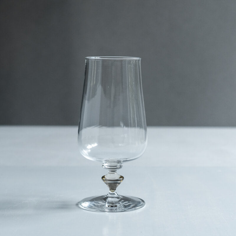 Clear stemmed drinking glass (cup) photographed on a flat surface against a gray background.