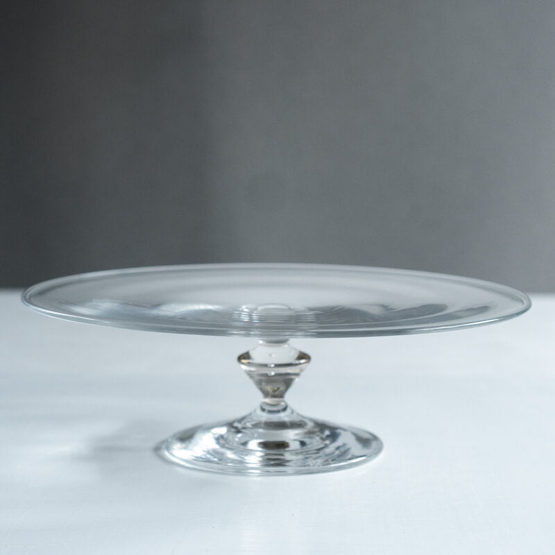 Clear Okutaiware compote L (flat) glass plate on a short pedestal against a neutral background.