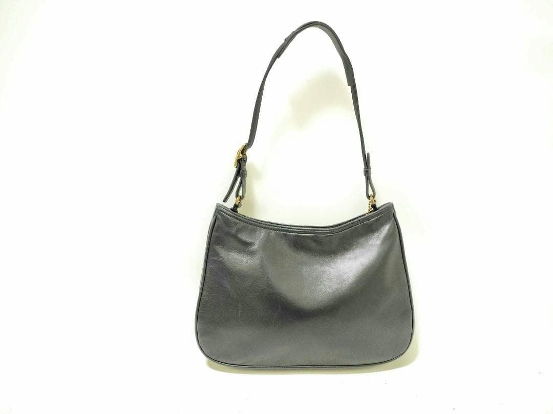 Black Coach lamb leather one-shoulder bag hanging against a white background.