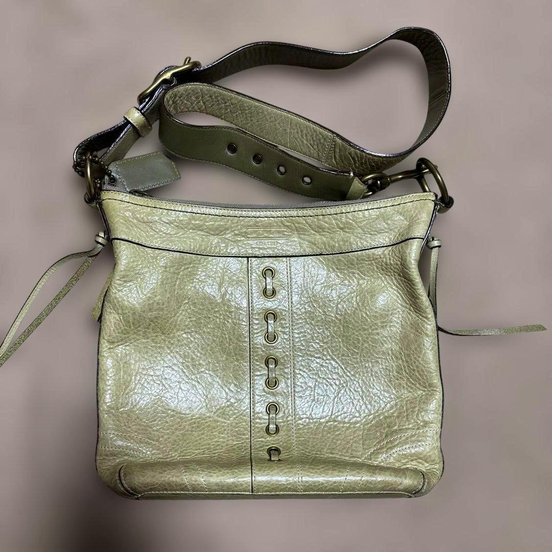 Front view of the light green Old Coach shoulder bag showing the adjustable strap and central grommet detailing.