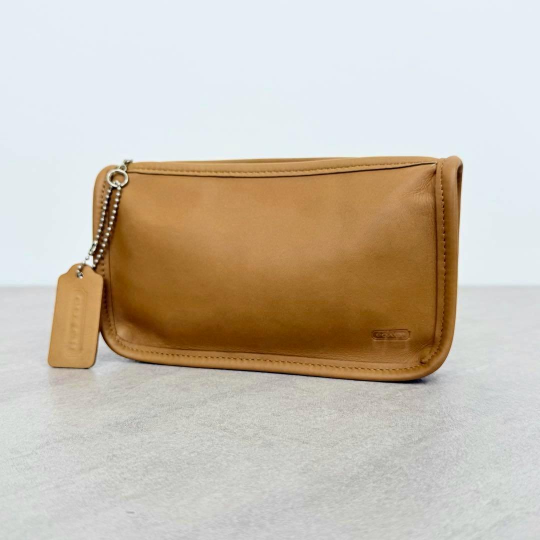 Beige OLDCOACH Chunky Case leather pouch shown front-on with attached leather tag and ball-chain zipper pull on a plain background.