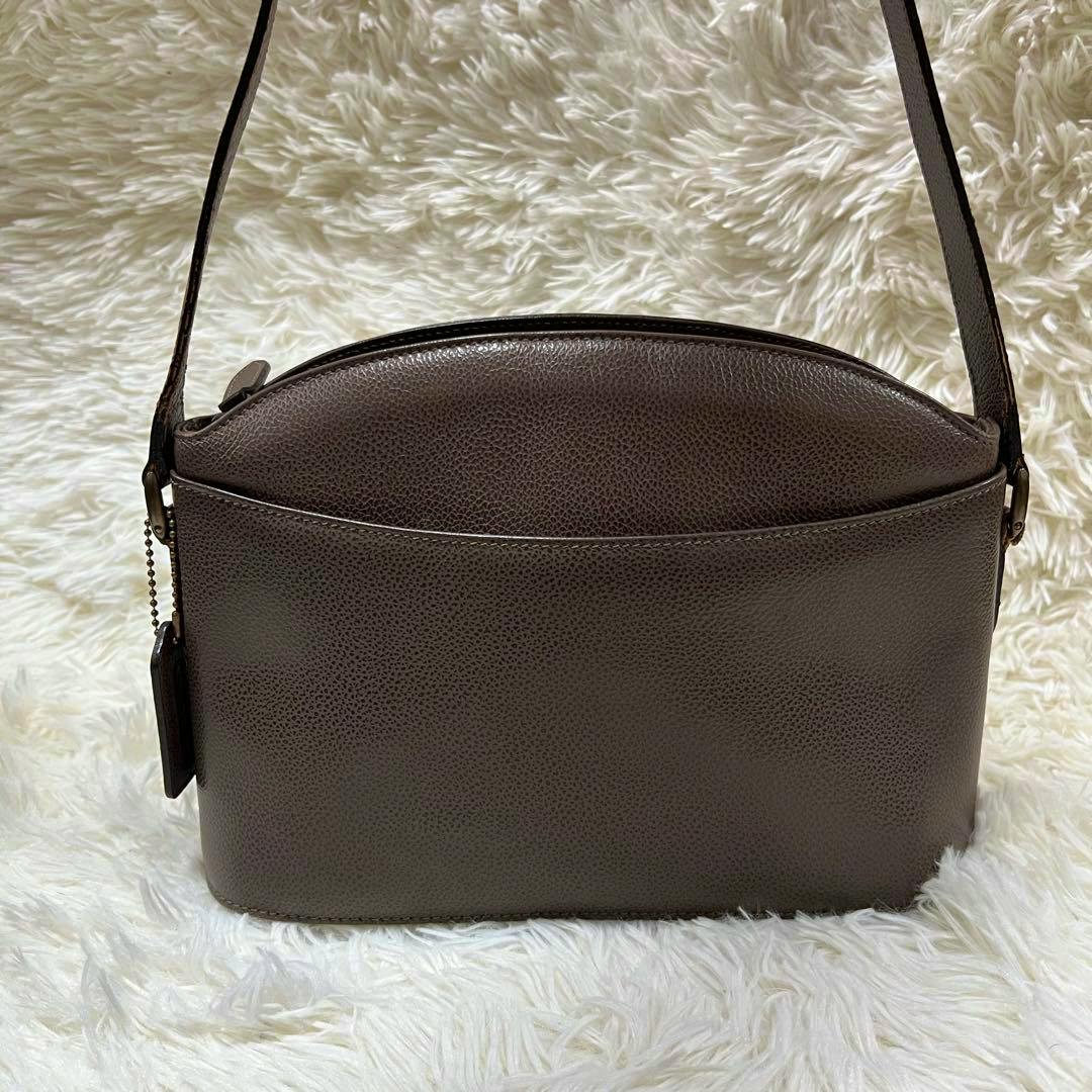 Front view of the OLD COACH cow leather brown crossbody shoulder bag on a white fur background.