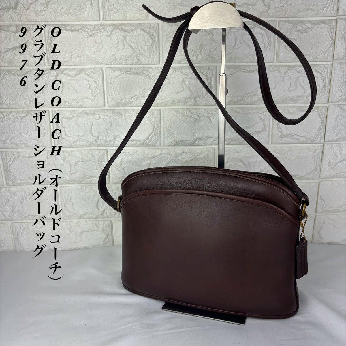 Dark brown OLD COACH cow leather shoulder bag (model 9976) hanging on a display stand against a tiled background.