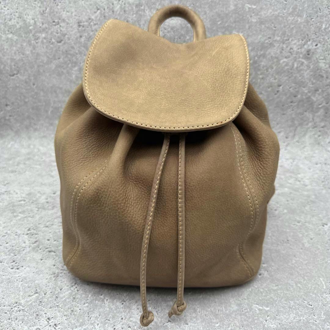 Front view of the OLD COACH beige nubuck leather backpack showing the drawstring closure and top flap.