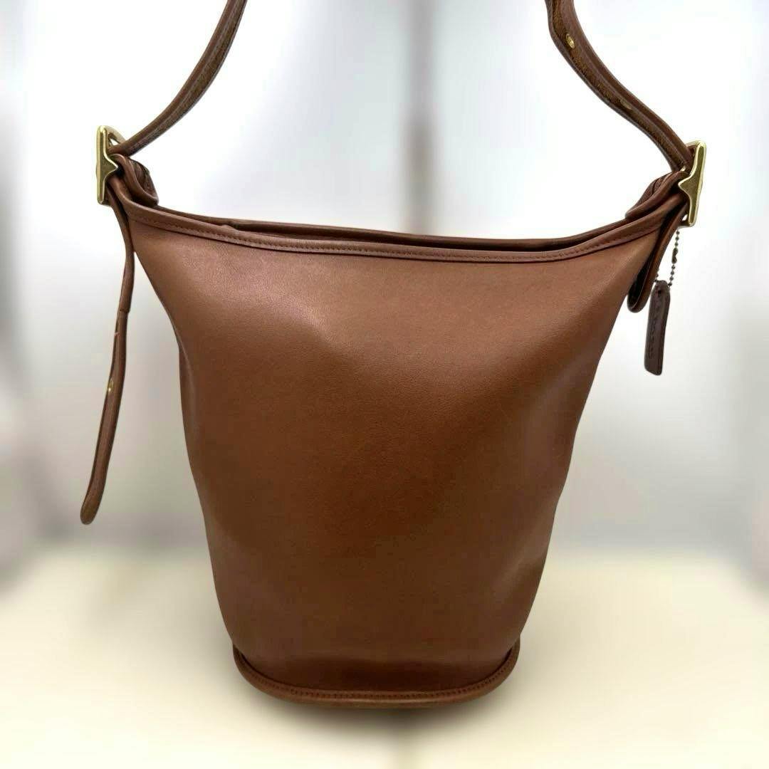 Front view of a brown grab-tan leather Coach shoulder bag with an adjustable strap and rounded base.