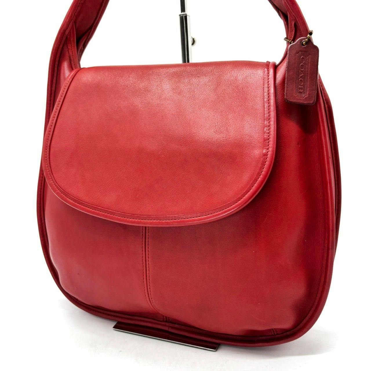 Front view of a red Coach leather shoulder bag with flap and leather hang tag.