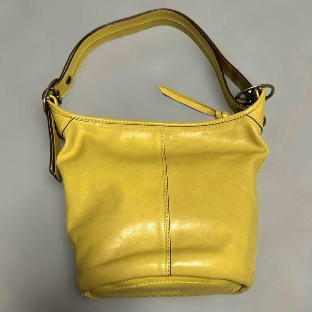 Yellow Coach leather shoulder bag shown from the front with a single short strap.