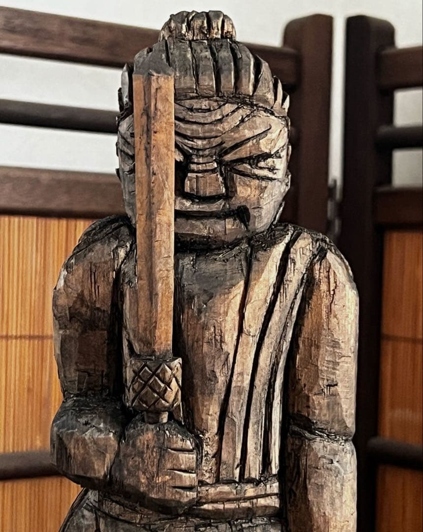 Front view of a carved wooden Fudō Myōō (Buddhist) statue showing the upper body holding a sword.