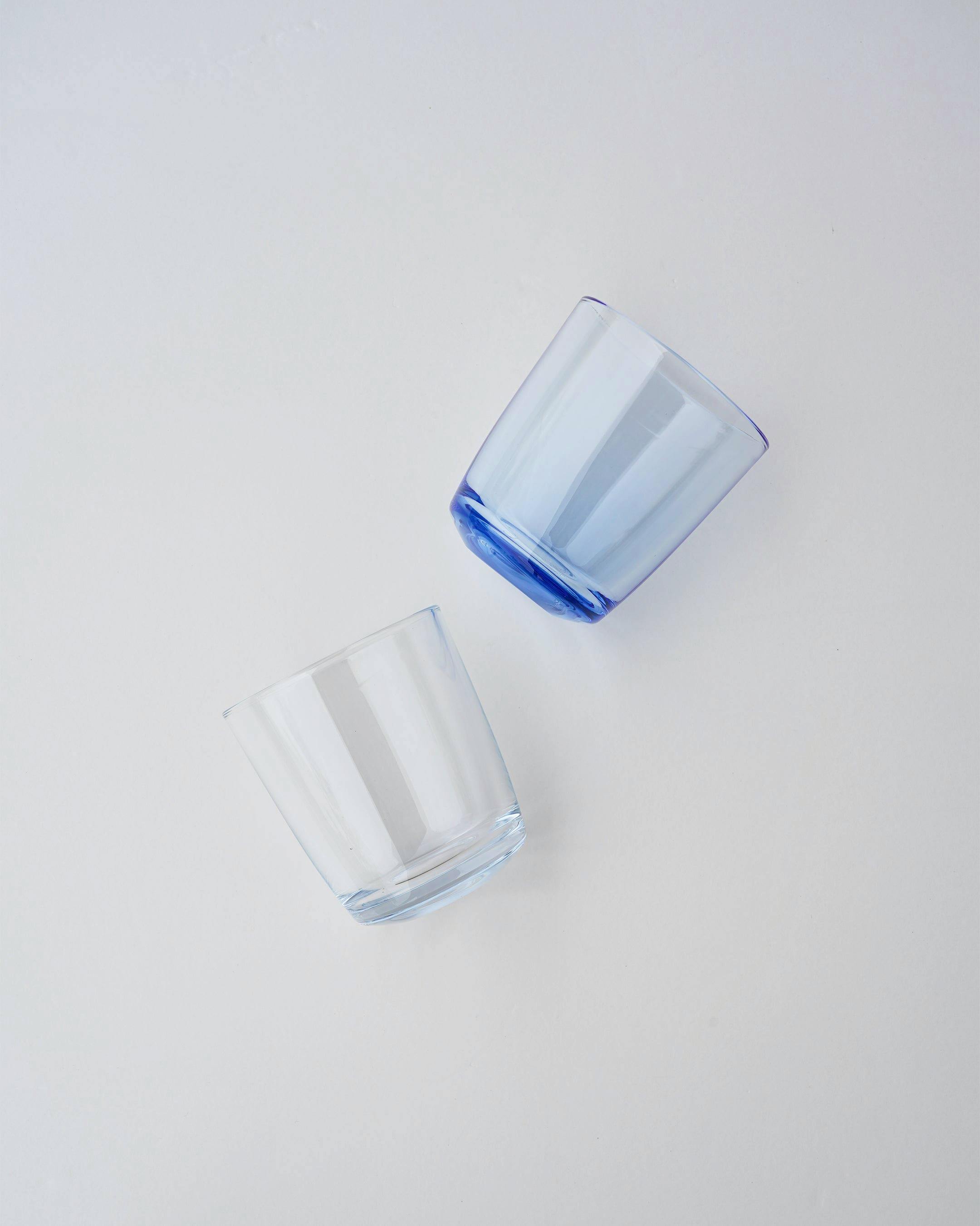 Two tumblers (one clear, one blue) shown on a white background, displaying their shape.