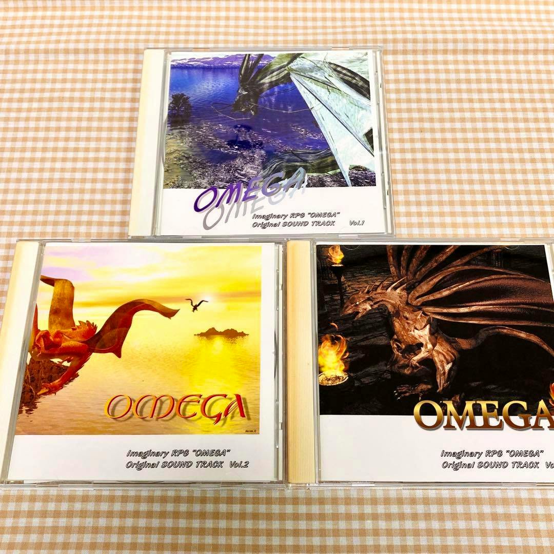 Three OMEGA SOUND TRACK CD jewel cases with their front cover artwork arranged on a checked cloth.