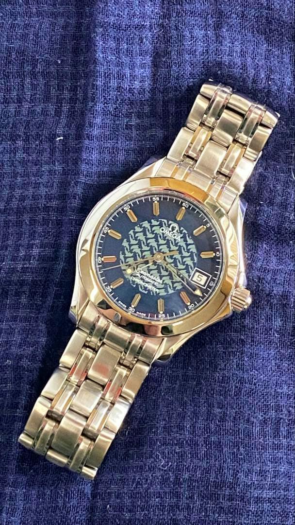 Omega Seamaster 120 automatic wristwatch with a patterned dark dial and metal bracelet lying on blue fabric.