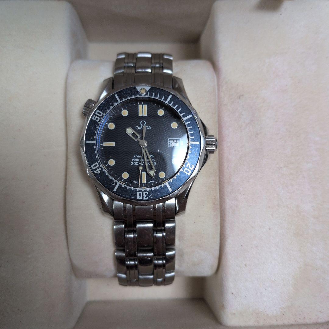 Front view of an Omega Seamaster 300 watch with metal bracelet on a beige cushion.