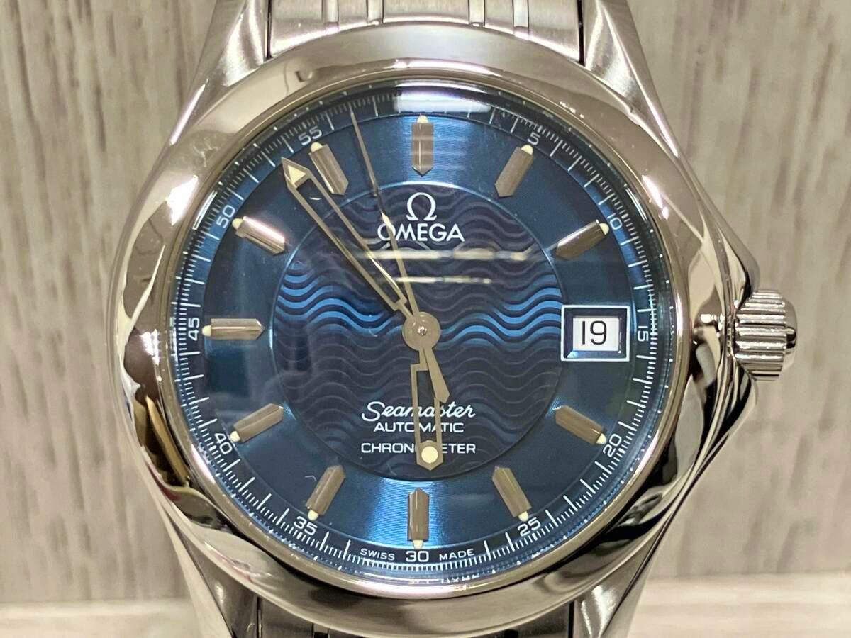 Close-up of an OMEGA Seamaster automatic wristwatch with a blue wave-pattern dial, date window, and stainless steel crown.