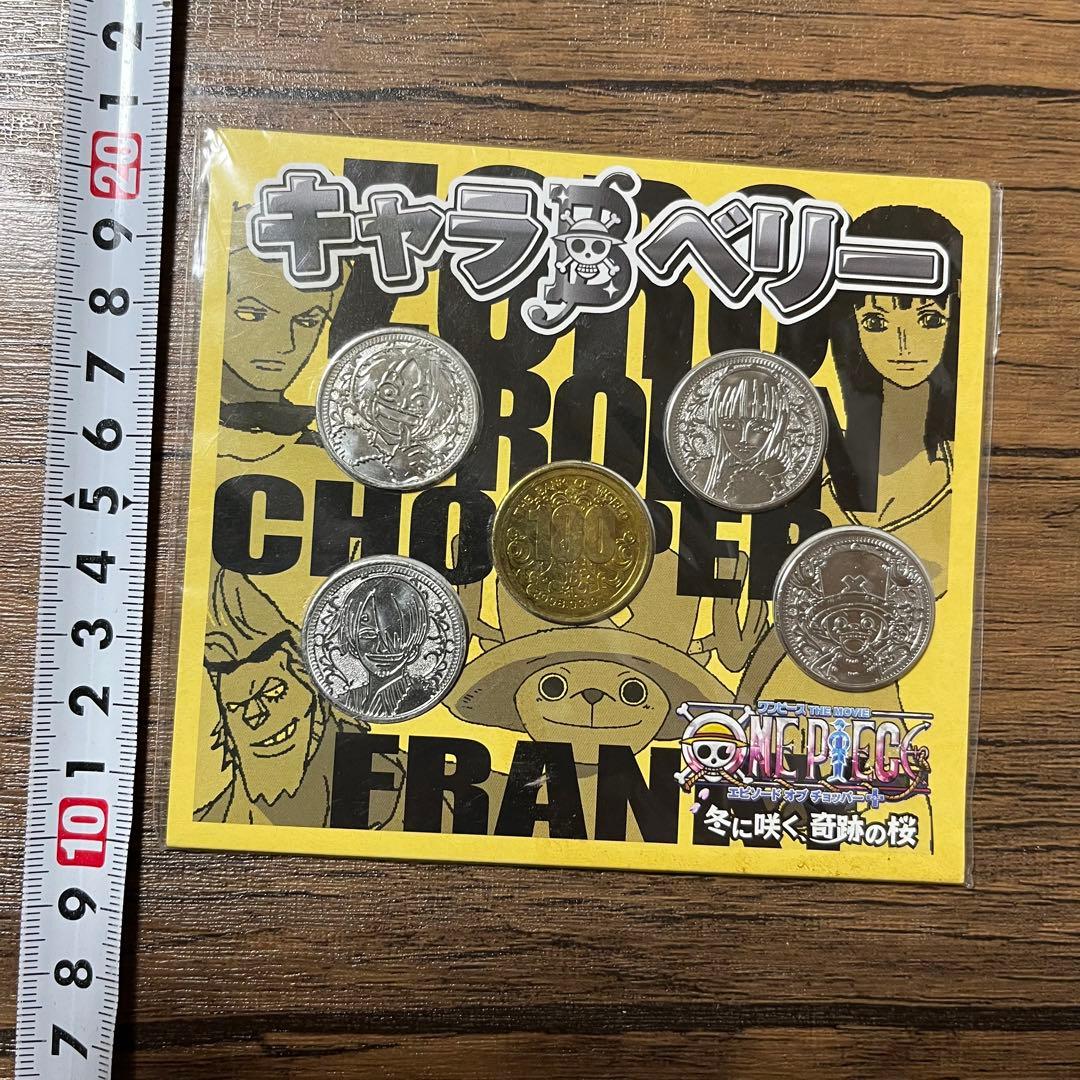 Photo of the One Piece movie bonus coin set (2008) showing six coins on a yellow backing card with a ruler at the left.