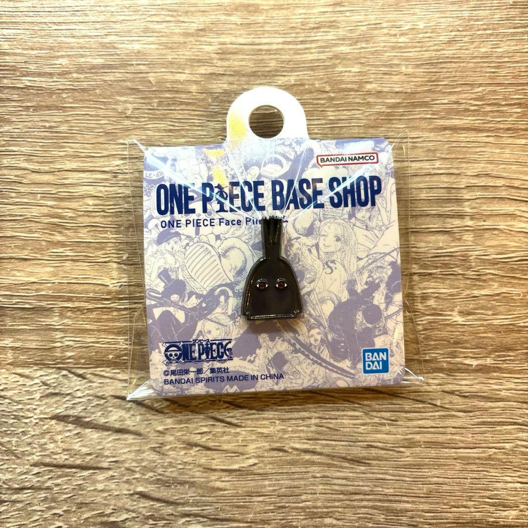 Packaged One Piece Face Pin attached to a 'ONE PIECE BASE SHOP' backing card on a wooden surface.