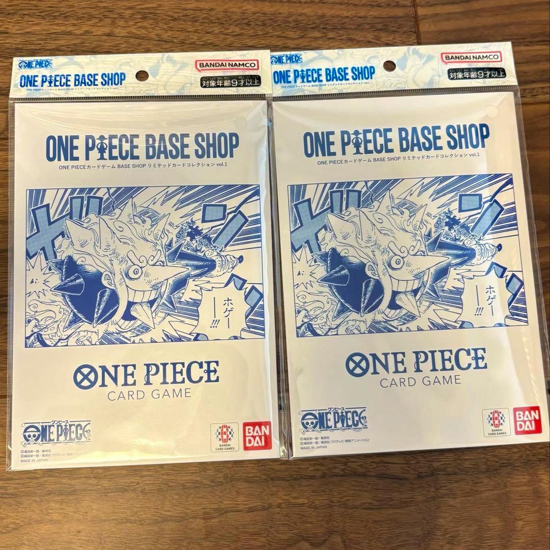 Two sealed ONE PIECE BASE SHOP リミテッドカードコレクション vol.1 card game packs with blue manga-style cover art and Bandai logos on a wooden surface.