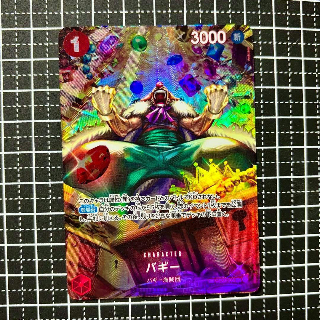 Holographic One Piece trading card of Buggy (バギー) with colorful foil details placed on a black grid mat.