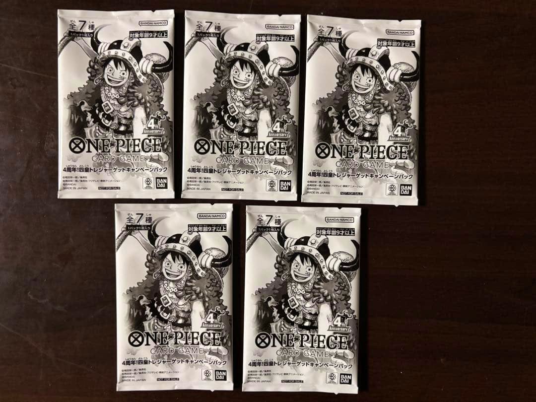Five sealed ONE PIECE Card Game 4th Anniversary campaign packs arranged on a dark surface.