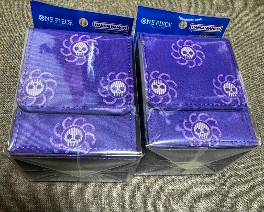 Two purple ONE PIECE card game card cases in plastic retail packaging with skull motif and Bandai Namco header.