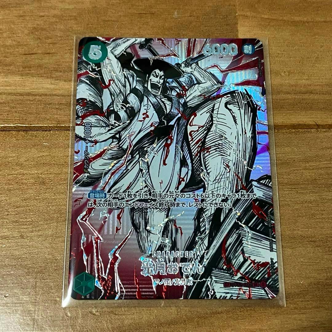 Front of the One Piece trading card 光月おでん (Kozuki Oden) with holographic foil in a clear sleeve on a wooden surface.