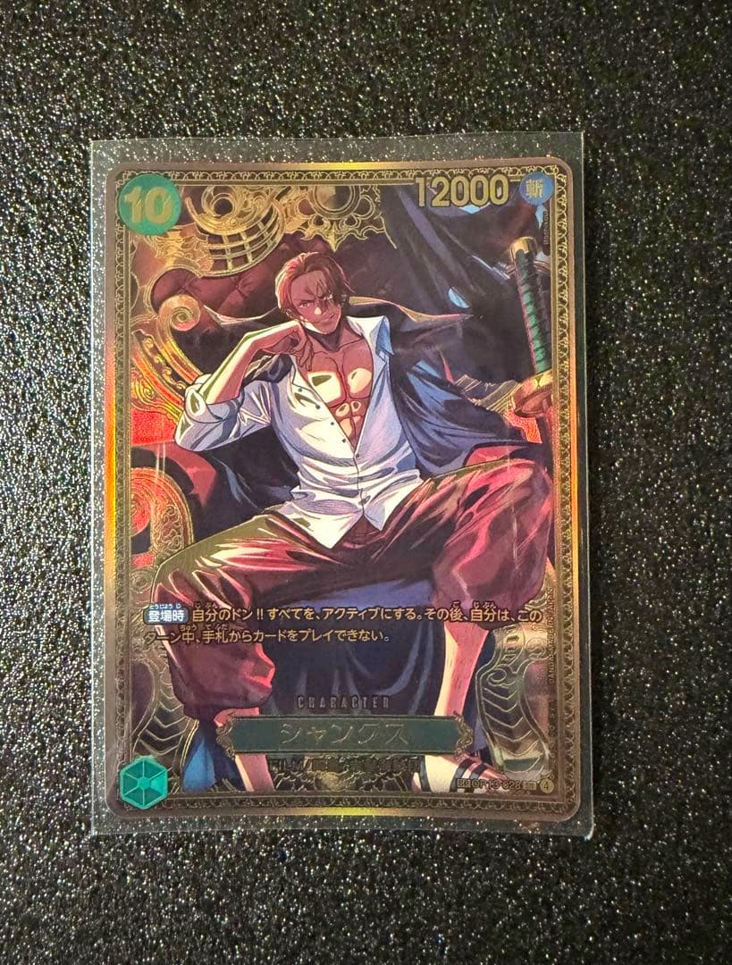 Front photo of the One Piece trading card OP13-028 SP Shanks showing the illustrated character seated with an open shirt and decorative gold border.