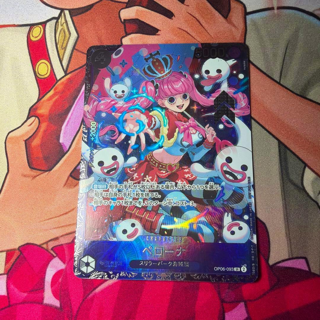 Holographic One Piece trading card of Perona with pink hair and ghost characters shown on a playmat.
