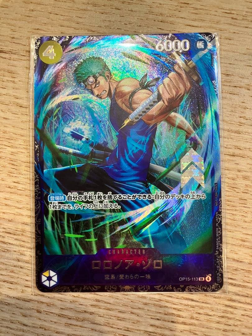Front of the One Piece trading card 'ロロノア・ゾロ OP15-113' showing Roronoa Zoro artwork with holographic foil and card text.