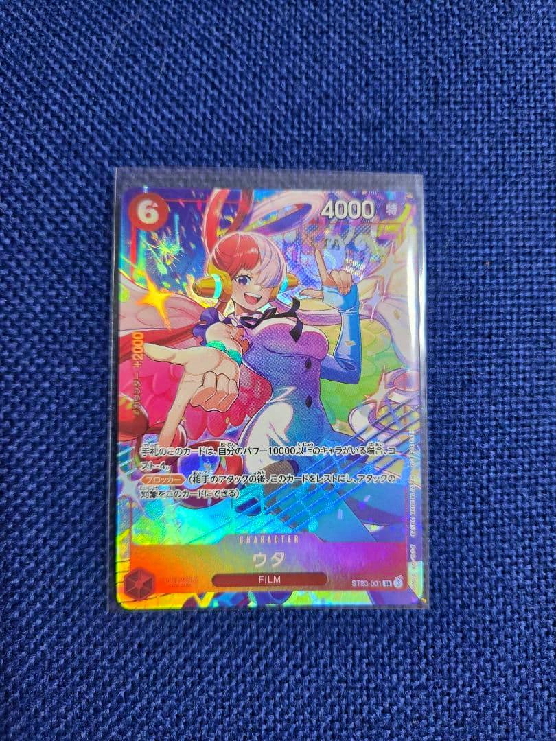 Front of the One Piece trading card (ワンピースカードゲーム ウタ ST23-001) showing the character Uta with holographic foil on a blue fabric background.