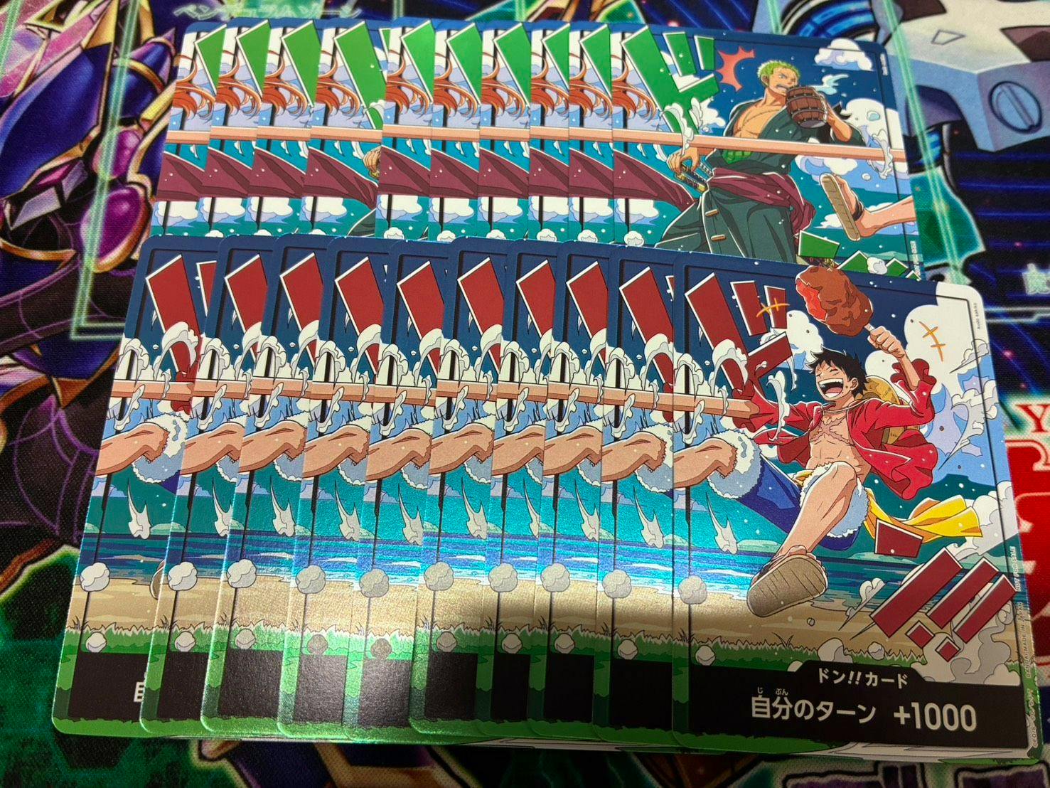 A spread of One Piece trading cards showing Luffy and Zoro arranged in overlapping rows on a playmat.