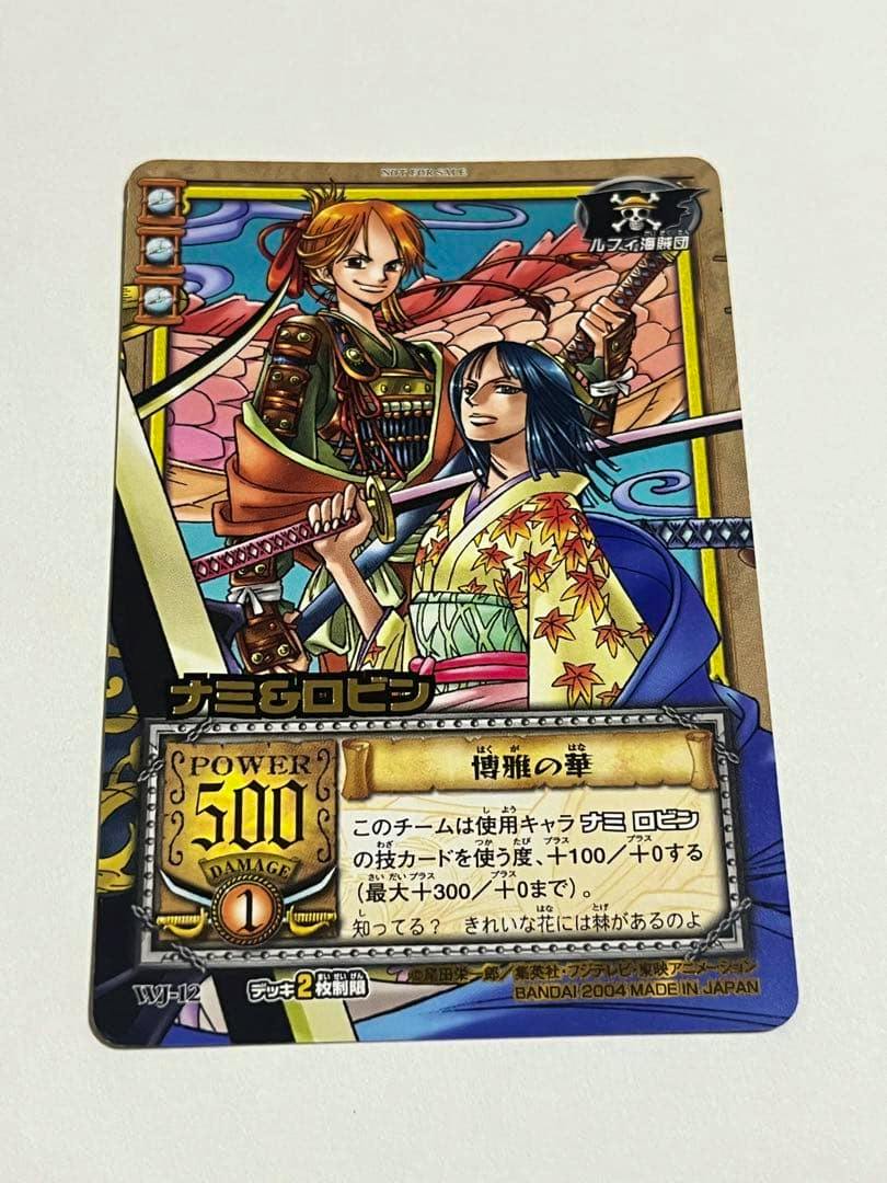 Photograph of the front of a One Piece trading card showing Nami and Robin artwork with Japanese text and stats.