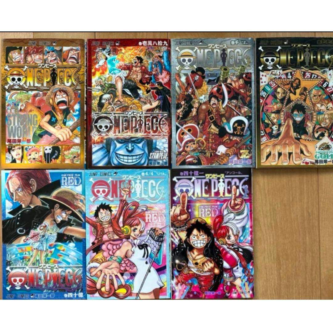 Several One Piece movie bonus books (特典本) with colorful covers arranged in a grid on a wooden surface.
