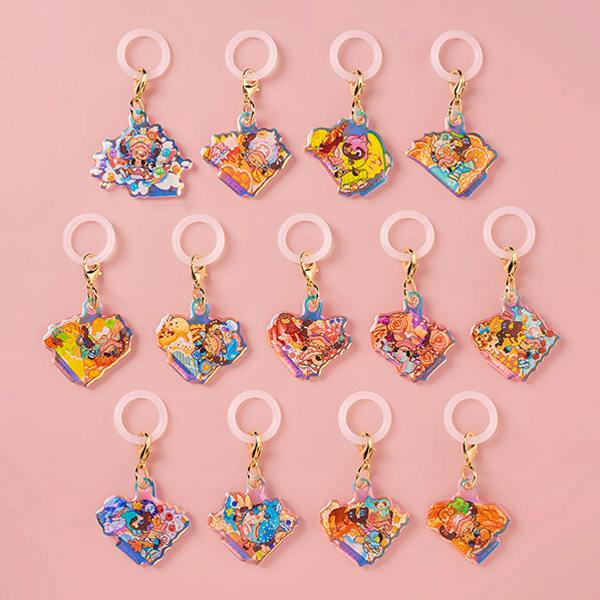 Photo of thirteen acrylic Chopper keychain charms arranged in rows on a pink background.