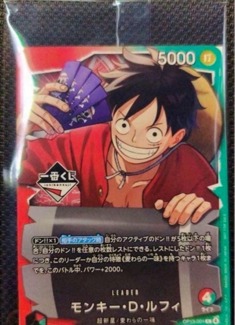 Photo of a One Piece trading card featuring Monkey D. Luffy smiling and holding purple cards, with Japanese text and logos.