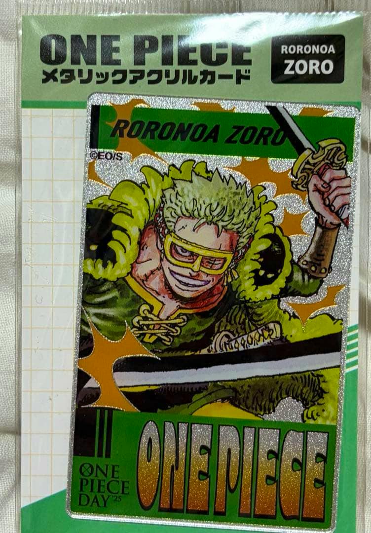 Packaged One Piece metallic acrylic card showing Roronoa Zoro in a green outfit with a glittery background and large "ONE PIECE" text.