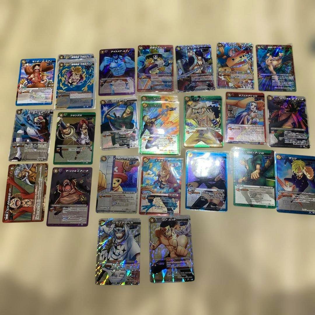 Multiple One Piece Miracle Battle Carddass trading cards with several holographic foil cards arranged on a beige surface.