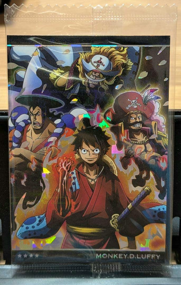 Sealed holographic One Piece photocard showing Monkey D. Luffy in a red outfit with a flaming arm and the text "MONKEY.D.LUFFY" at the bottom.