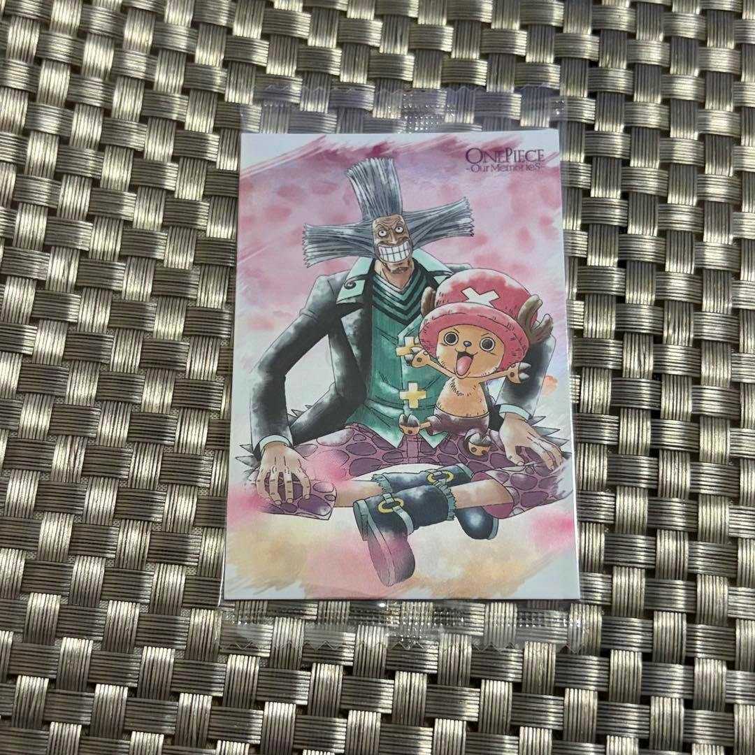 Photocard from ONEPIECE “our memories” showing Chopper and another One Piece character on a pink background placed on a woven mat.