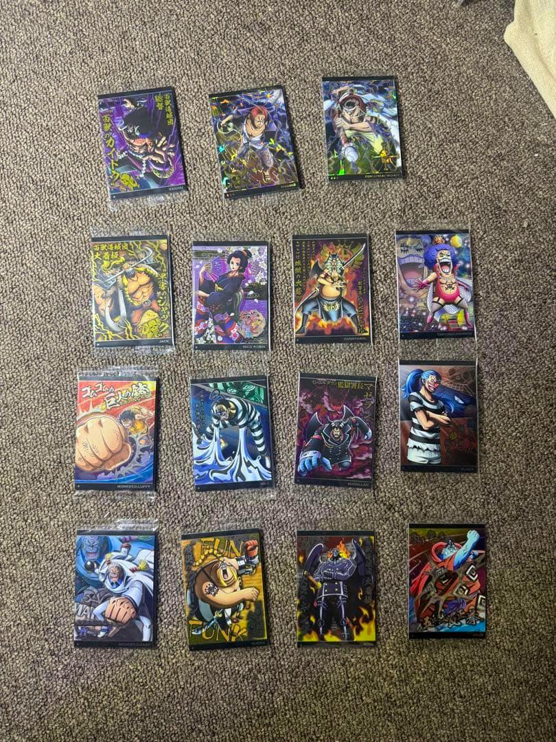 Fifteen One Piece wafer photocard fronts displayed on a carpeted surface.