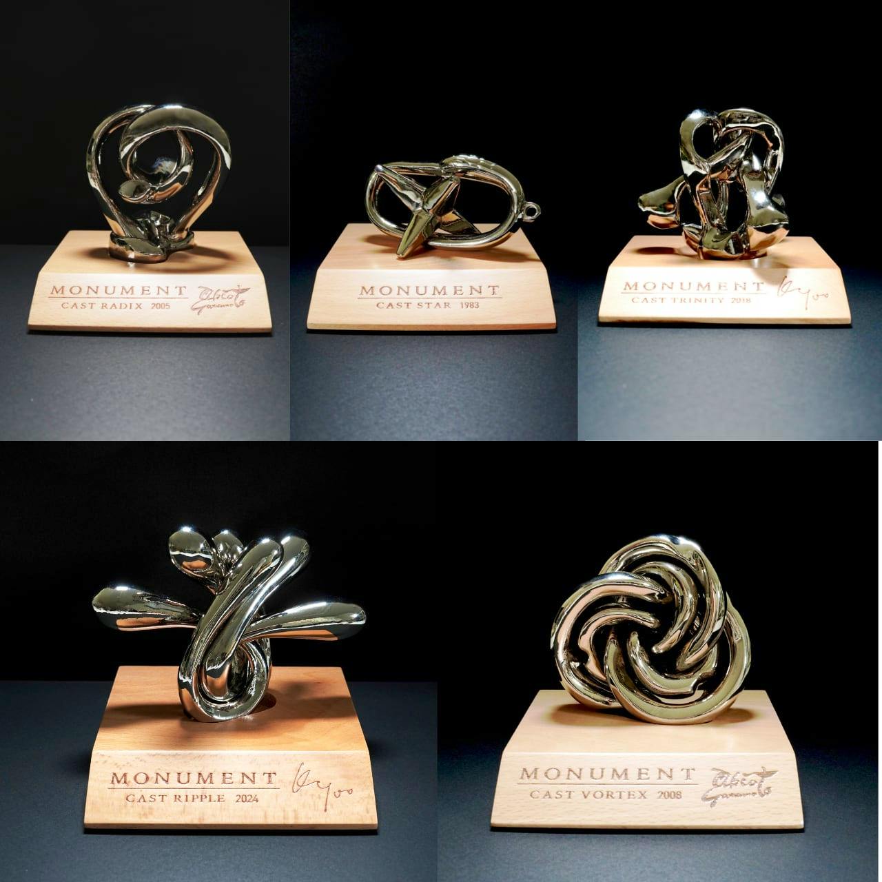 Five zinc-alloy MONUMENT toy sculptures displayed on wooden bases, each labeled with its cast name and year.
