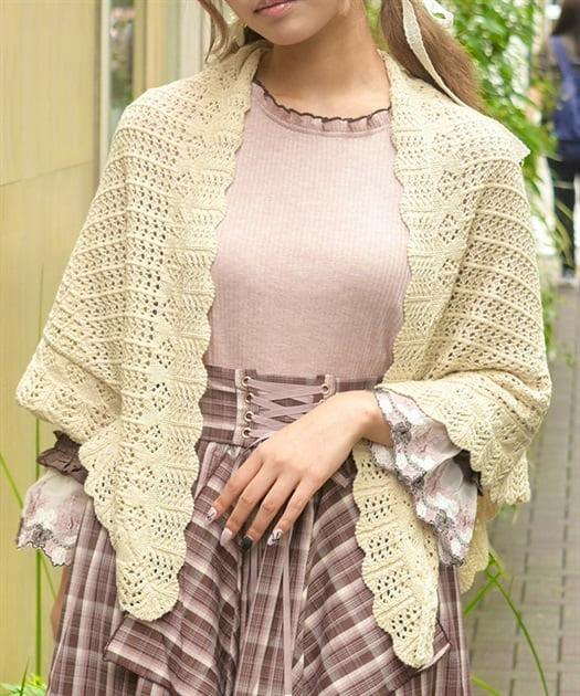 Model wearing a cream lace-knit triangular shawl draped over her shoulders.