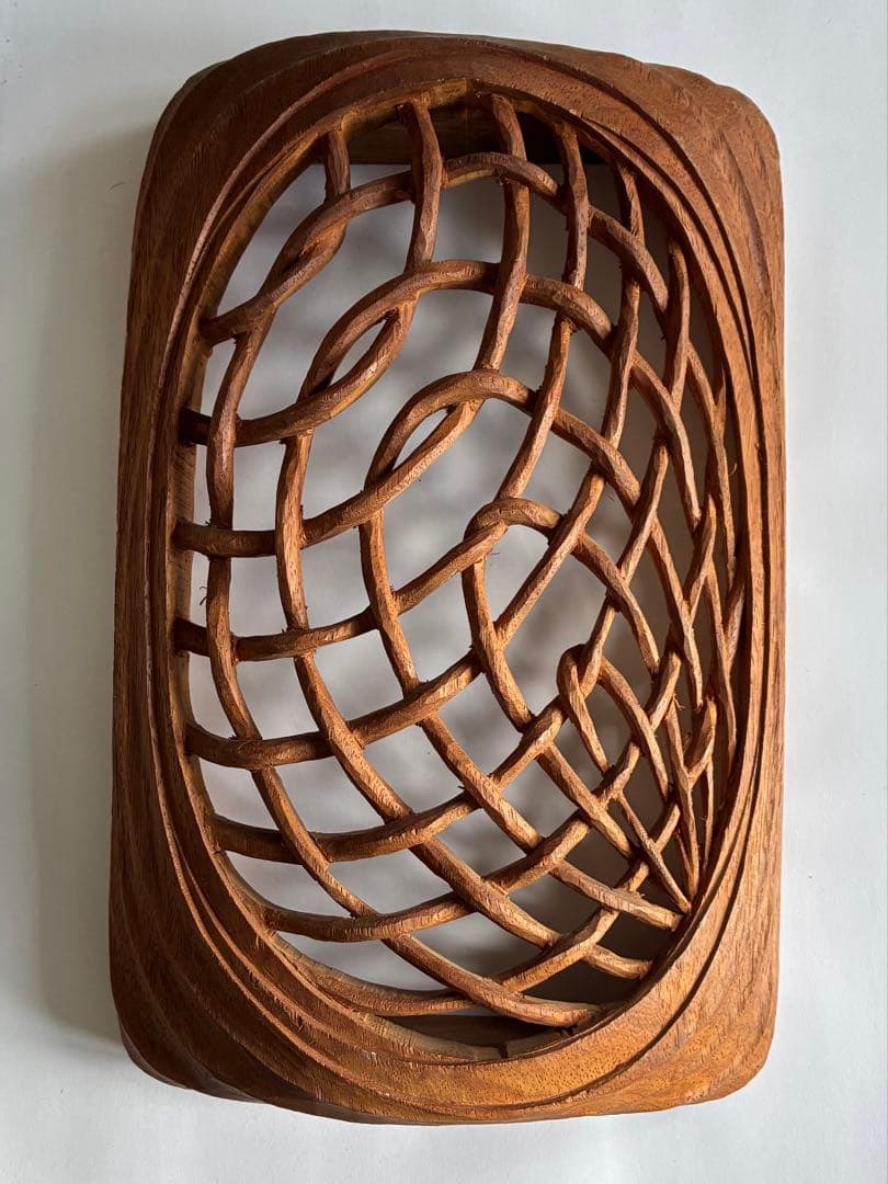 Rectangular wooden openwork carving (透し彫り) showing an oval interlaced lattice pattern photographed from above.