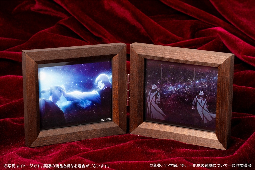 Open wooden double-frame music box displayed on red velvet showing two illustrated panels inside.