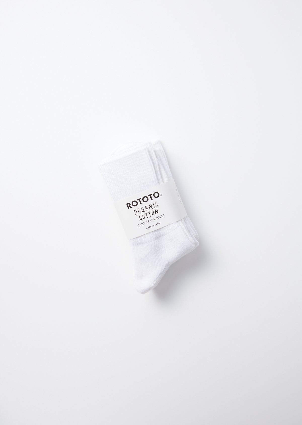 Folded white rib crew socks with a paper label reading "ROTOTO ORGANIC COTTON" on a white background.