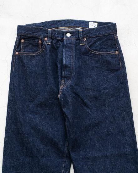 Front view of men's selvedge denim jeans laid flat showing the waistband, pockets, and upper legs.