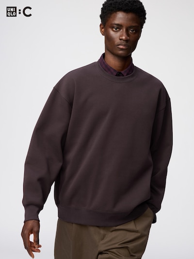 A model wearing a dark oversized sweatshirt shown from the front.