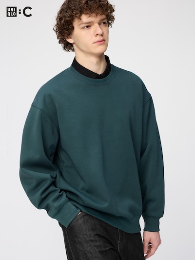 A male model wearing a dark teal oversized sweatshirt.