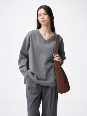 Model wearing a gray oversized V-neck knit pullover sweater.