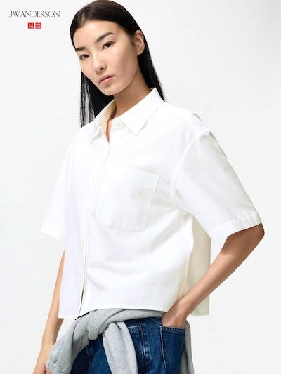 A model wearing a white oxford oversized short-sleeve children's shirt shown from a three-quarter view.