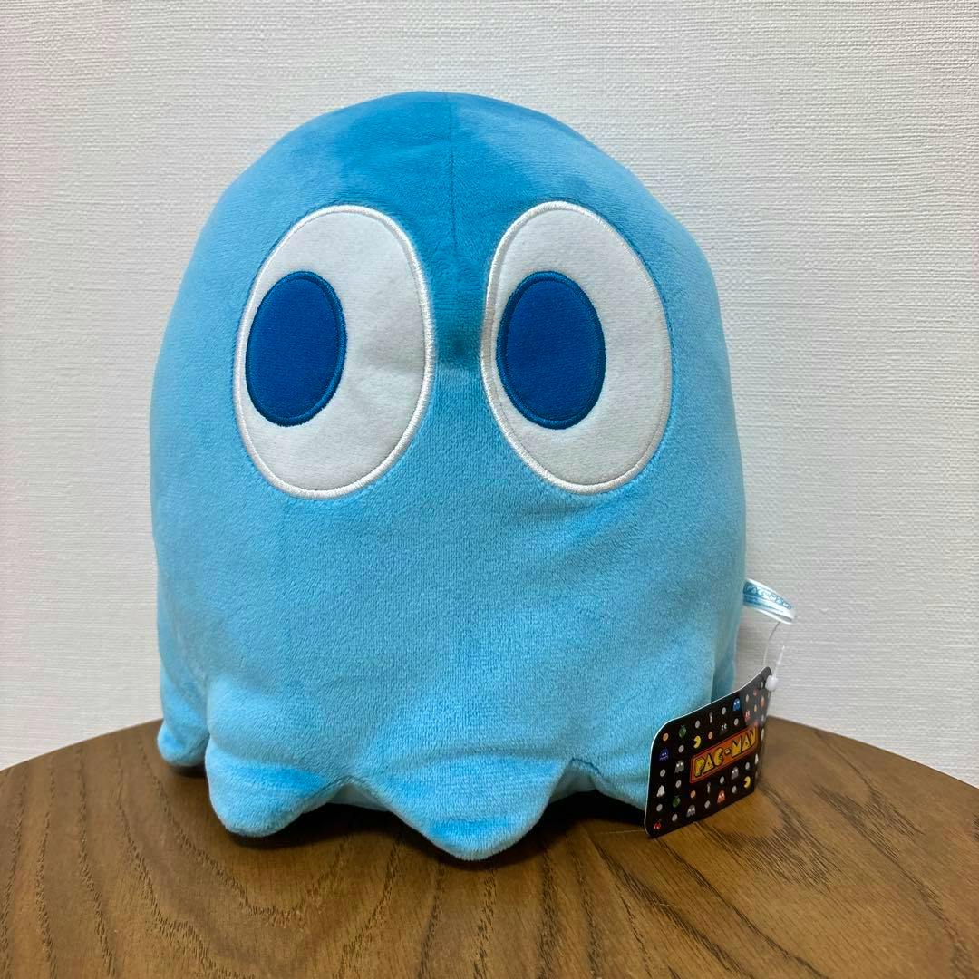 Blue Pac-Man MB plush ghost (アオスケ) on a wooden table with its tag visible.