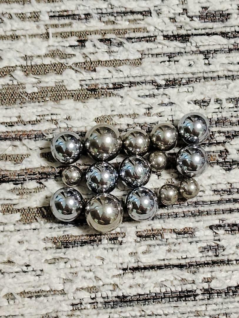 Shiny metallic pachinko balls arranged on a textured fabric background.